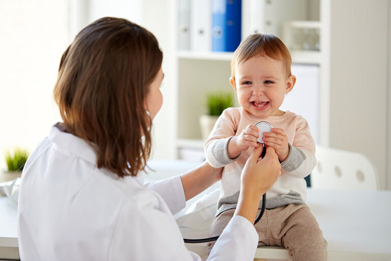 smiling toddler at a well visit with their doctor