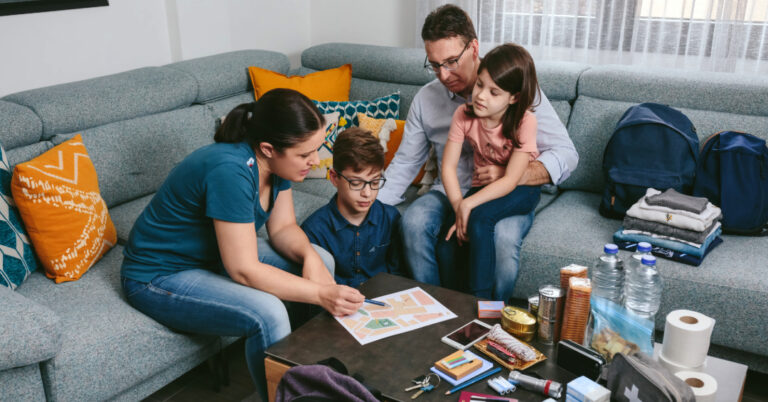 Family sitting on couch and reviewing their emergency plan with emergency items on the coffee table nearby.