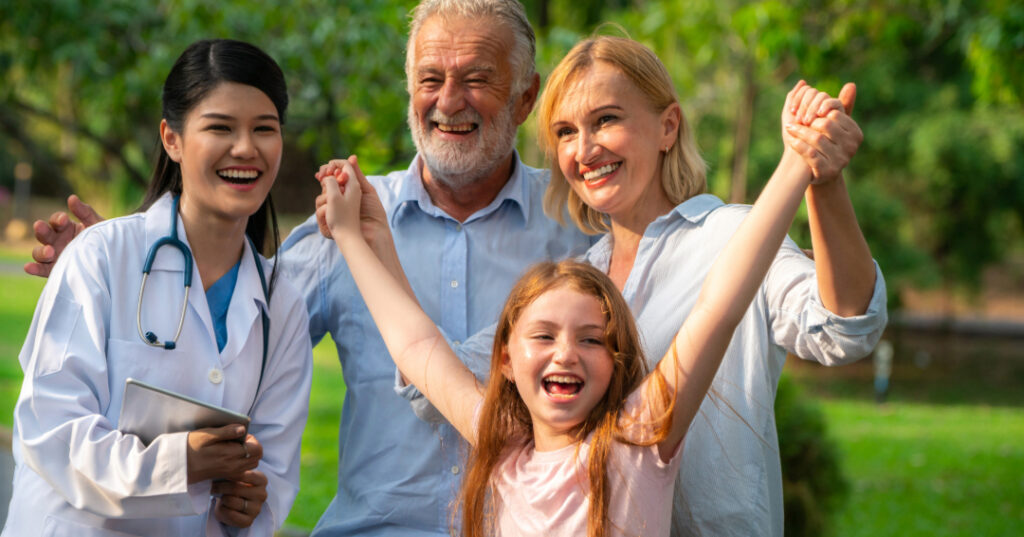 Pediatrician and family with daughter celebrating community health at a park.
