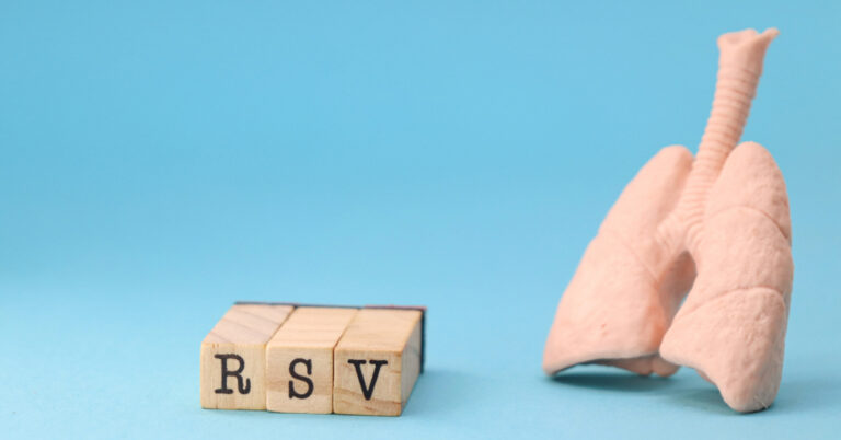 Wooden blocks with RSV printed on them next to a model of lungs.